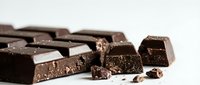 Dark chocolate pieces and crumbs scattered on white background, isolated for confectionery, baking, food photography, and culinary design projects.