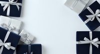 Wrapped gift boxes in navy and silver with white ribbons arranged on white background, overhead flat lay composition for holiday, celebration, and festive design projects.