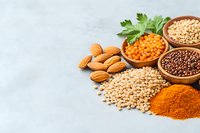 Healthy protein sources and spices with almonds, red lentils, quinoa, and turmeric powder arranged on light background. Nutritious vegetarian ingredients.