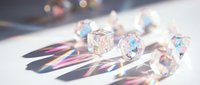 Sparkling crystal prisms casting rainbow light reflections on white surface with colorful bokeh background for luxury decoration and optical effects.