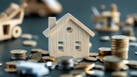 Wooden house model surrounded by coins and keys representing real estate investment, mortgage planning, property savings and home financing concepts.