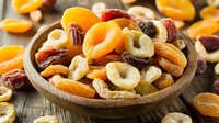 Mixed dried fruits and nuts in wooden bowl on rustic table, healthy snack with apricots, dates, cashews. Natural food photography for packaging.