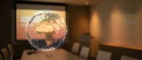 Transparent glass globe showing Africa and Europe continents floating in modern conference room with presentation screen and meeting table.