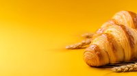 Fresh baked croissants and wheat ears on vibrant yellow background with copy space, morning breakfast pastry concept for bakery or cafe menu.