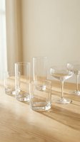 Clear glassware collection on wooden table with warm natural lighting for kitchen and dining room decor in minimalist home interior design.
