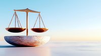 Brass balance scale on marble base against soft gradient background symbolizing justice, law, and equilibrium in legal and business concepts.