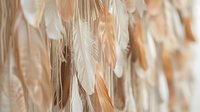 Soft feathers in warm beige and cream tones creating elegant natural texture for bohemian decor, wedding backdrop, or artistic design projects.