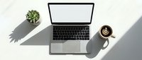 Modern laptop computer with blank white screen on clean white desk workspace with coffee cup and small succulent plant for remote work and productivity.