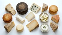 Assorted artisanal cheese selection featuring aged cheddar, blue cheese, goat cheese and soft varieties arranged on white background for food styling and culinary projects.