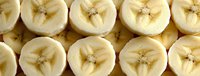 Fresh sliced bananas arranged in rows showing cross sections with star pattern in center, natural organic fruit texture and pattern for healthy food background.