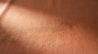 Close-up of warm terracotta fabric texture with natural light creating subtle shadows and highlights across woven material surface.