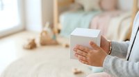 Woman holding white box in bedroom, unpacking or receiving gift package, moving day or online shopping delivery concept.