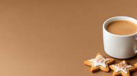 Cozy winter composition with coffee cup and star-shaped gingerbread cookies with icing on brown background. Festive holiday drink and treats setup.