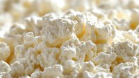 Fresh cottage cheese macro shot showing soft white curds with creamy texture and natural dairy appearance, suitable for food photography and culinary content.