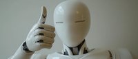 White humanoid robot giving thumbs up gesture against neutral background, showing positive artificial intelligence concept in modern robotics technology.