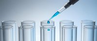 Laboratory pipette dispensing blue liquid into test tubes for scientific research and chemical analysis experiments.