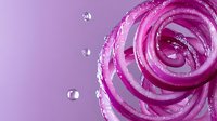 Vibrant pink cosmetic cream swirl with water droplets on purple background, showcasing skincare product texture for beauty industry advertising.