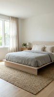 Minimalist bedroom interior with wooden platform bed, neutral bedding, jute rug and natural light from large window for modern home design.