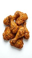 Crispy fried chicken pieces with golden-brown seasoned coating, isolated on white background for food photography, restaurant menus, and culinary design projects.