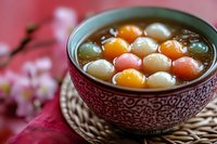 Traditional Chinese tangyuan glutinous rice balls in sweet syrup served in decorative bowl for Lunar New Year celebration dessert.