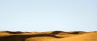 Golden sand dunes landscape with rolling hills under clear sky, desert scenery for travel and nature backgrounds.