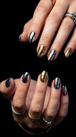 Stylish metallic nail art with geometric patterns in gold, silver and blue tones on female hands against black background for beauty and fashion concepts.