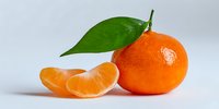 Fresh mandarin orange with green leaf and peeled segments on white background, showcasing vibrant color and juicy texture for food photography.