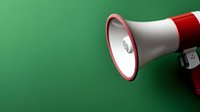 Red and white megaphone on green background with dramatic lighting and copy space, communication and announcement concept for marketing and promotion.