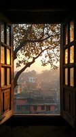 Open wooden window frames reveal misty sunrise over terracotta rooftops with tree branches silhouetted against golden morning light, creating atmospheric urban scene.