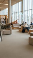 Hand touching holographic display with scientific formulas in modern office space with colleagues collaborating in background, representing innovation and technology integration in workplace.