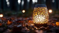 Glowing mason jar lantern with intricate pattern casting warm light on autumn leaves at dusk, creating magical ambiance in forest setting.