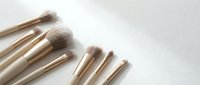 Set of professional makeup brushes with soft bristles and gold handles arranged on a white surface, beauty tools for cosmetic application.