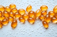 Golden omega-3 fish oil capsules arranged on wet surface with water droplets, showcasing health supplement for nutrition and wellness.