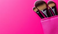Professional makeup brushes in pink leather case against vibrant pink background, minimal beauty concept with copy space for text.