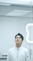 Young Asian male professional wearing glasses and white jacket in modern office environment with neon lighting, suitable for corporate, technology, and business concepts.