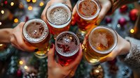 Friends toasting with craft beer glasses during festive holiday celebration with warm bokeh lights and Christmas decorations in cozy pub atmosphere.