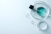 Glass dropper bottle with turquoise liquid and water drops on light background, minimalist cosmetic skincare product photography for beauty industry.