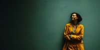 Young African American woman in orange blazer smiling confidently against teal background for business and lifestyle marketing campaigns.