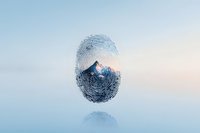 Mountain peak landscape creatively composed within fingerprint silhouette on soft blue background, representing nature and human identity connection.