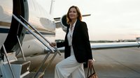 Professional businesswoman in elegant black blazer boarding private jet at sunset, representing luxury travel, corporate success, and executive lifestyle.