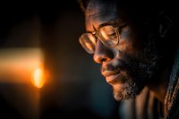 African American man with glasses and beard in warm golden light creating contemplative mood for lifestyle and portrait photography.