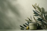 Olive oil cosmetic jar with fresh olive branch on neutral background with natural shadows for skincare and beauty product mockup.