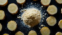 Fresh ginger root slices arranged in circular pattern around pile of ground ginger powder on dark background, overhead view of aromatic spice preparation.