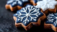 Festive navy blue and white snowflake cookies with intricate icing designs on dark background, perfect for winter holiday celebrations.