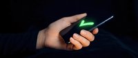 Male hand holding smartphone with glowing green checkmark on dark background, symbolizing approval, success, and digital validation for technology and business concepts.
