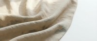 Soft beige linen fabric with natural wrinkles and folds creating elegant textile waves on white background for home decor and fashion design projects.