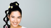 Young woman with East Asian ethnicity, styled hair in bun with yellow flowers, smiling at camera against neutral background. Portrait for beauty, fashion, lifestyle, and wellness content.