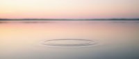 Serene water surface at dawn with gentle ripples forming concentric circles, creating a minimalist landscape for meditation and wellness concepts.