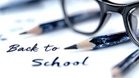 Back to school handwritten text with black rimmed glasses and pencils on white paper, shallow depth of field creates soft dreamy educational atmosphere.