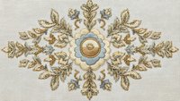 Ornate gold and blue embroidered floral motif with decorative leaves and central medallion on cream fabric background for luxury textile design projects.